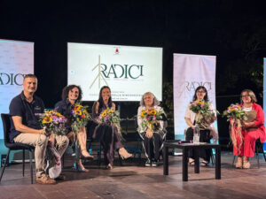Relatori sul palco della conferenza Radici con i mazzi di fiori